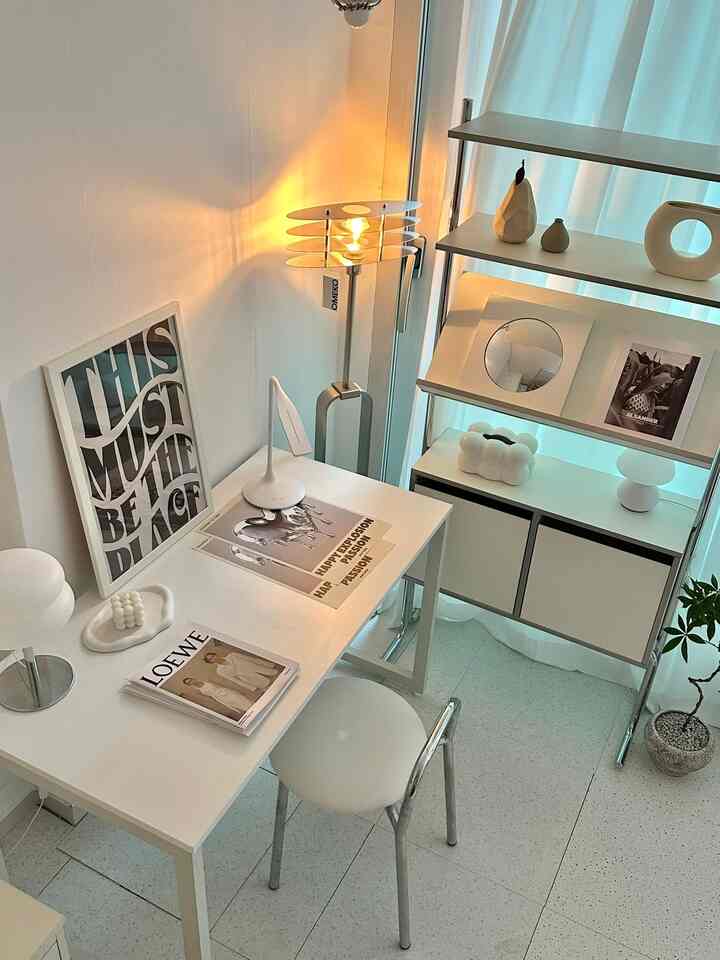 明るいホワイトトーンのシンプルモダンなホームオフィス、白いデスクとスツール、フロアランプ、棚が配置された清潔感のあるインテリア