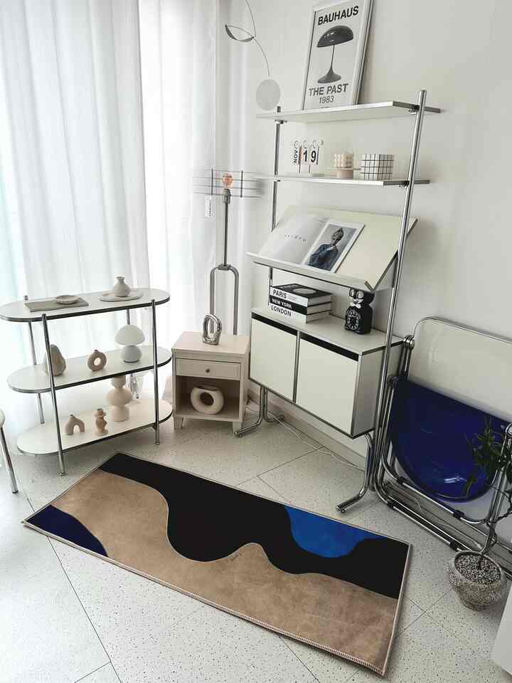 ベージュとブルーのトーンが特徴的なリビング、モダンな家具とミッドセンチュリースタイルのラグが配置された印象的な空間