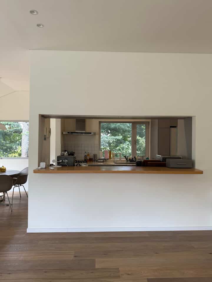 白とブラウンの木目調が調和したオープンキッチン、隣接するダイニングテーブルと椅子が配置された自然な雰囲気のリビングスペース