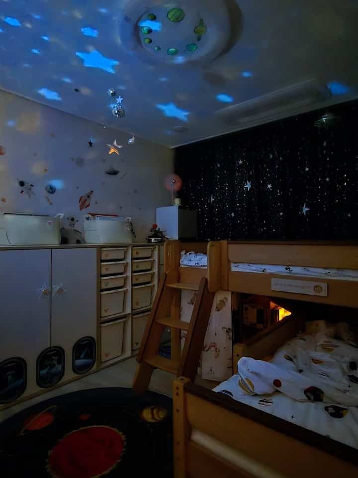 ネイビーと木目調の調和した子供部屋、星柄の遮光カーテンと二段ベッドが配置された印象的な寝室