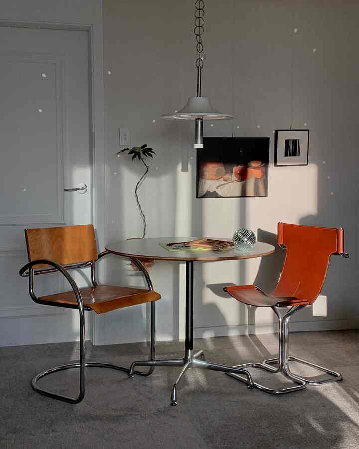 白い壁とナチュラルなブラウン家具が配置されたダイニング、丸いテーブルと革の椅子が調和する雰囲気のあるインテリア