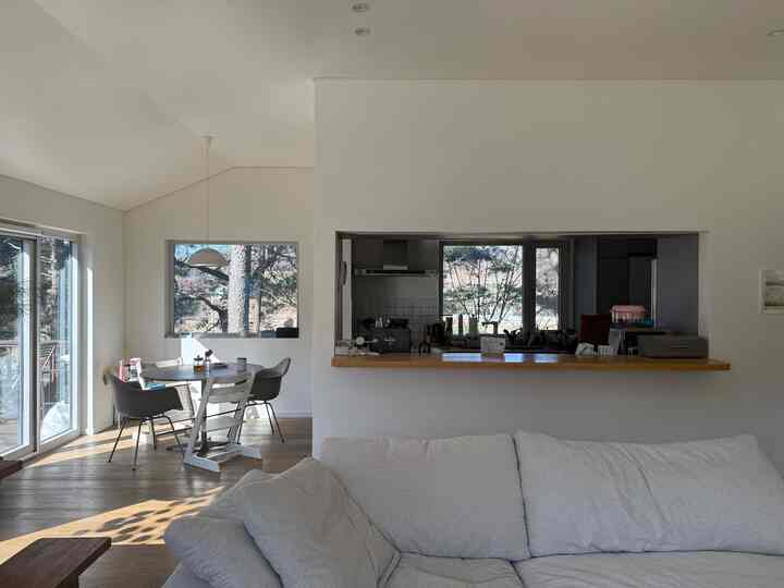 白と木目調のキッチンとダイニングが自然光を浴びて配置された、雰囲気のあるナチュラルモダンなインテリア