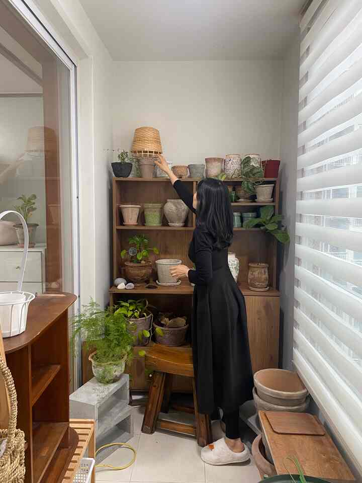 ナチュラルな色調のベランダ空間、木製の棚と多様なヴィンテージの土鍋、植物が調和した落ち着いた雰囲気のインテリア