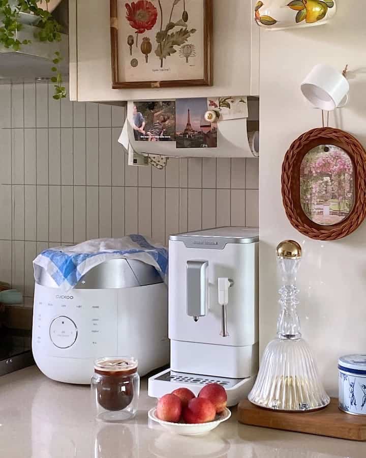 清潔感のある白を基調としたキッチンで、全自動コーヒーマシンや炊飯器、グラスが配置された印象的なカフェ風の空間