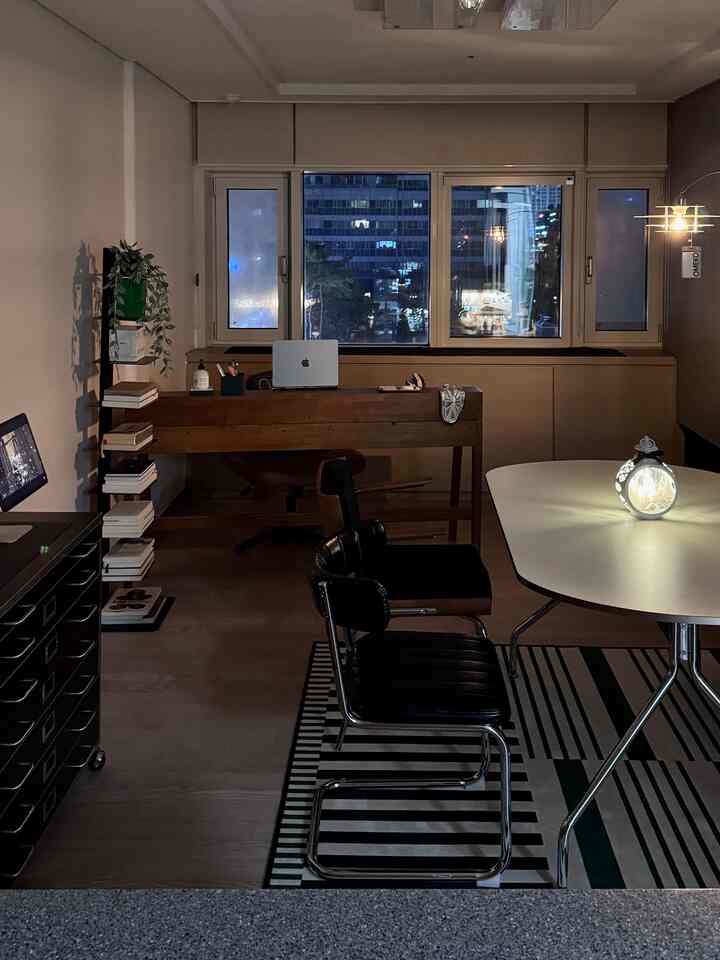 柔らかなナチュラルウッドトーンの書斎、木製デスクとオフィスチェアを配置し、夜の温かな照明が印象的な空間