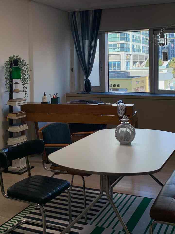 ナチュラルカラーのリビング、木製のデスクと様々な椅子が配置された落ち着いた雰囲気のインテリア