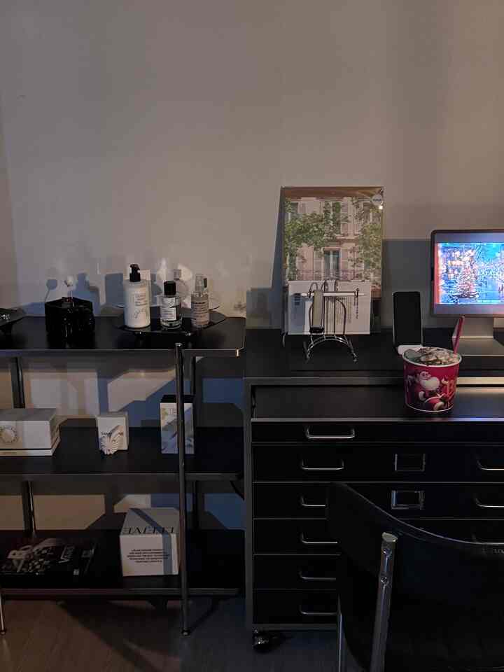 暗い照明の中、黒を基調としたデスクとドレッサーが配置され、さまざまな小物が置かれたモダンなホームシネマ空間