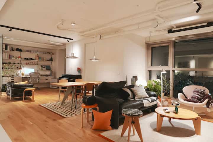 ナチュラルな木目調と黒い家具が配置されたモダンなリビングとホームオフィスのある空間