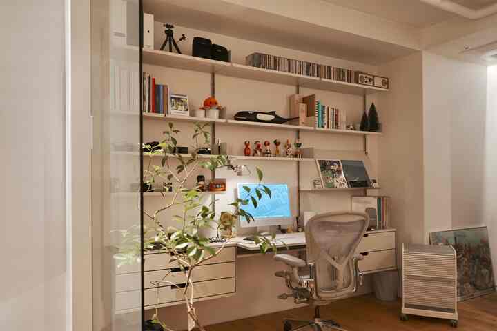 ホワイトと木目調の床が調和するモダンな書斎空間、Vitsoe 606のシェルフとエアロンチェアが配された整ったホームオフィス