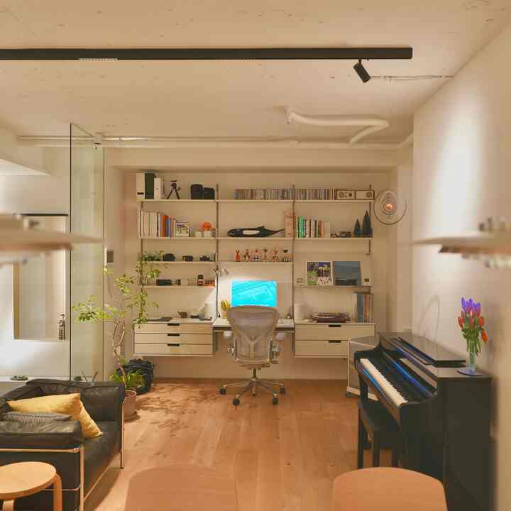 暖かいブラウンの木目調床と白い壁の北欧スタイルのホームオフィス兼リビング、中央に机とオフィスチェアが配置された雰囲気のあるインテリア