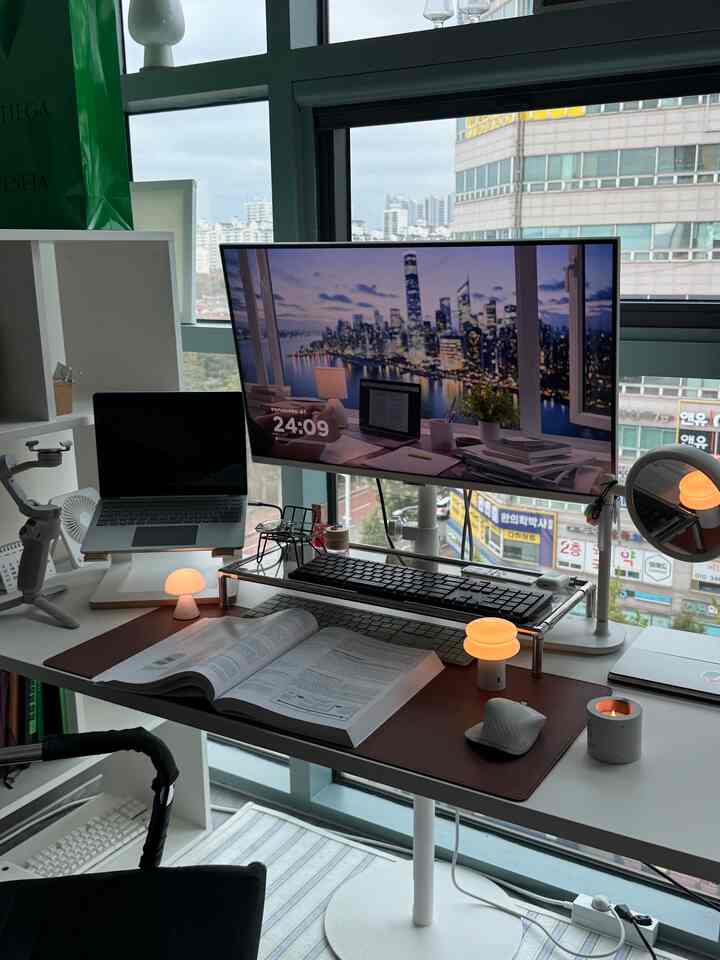 落ち着いたグレーとホワイトのトーンのホームオフィス空間、大型モニターと整ったデスクが印象的な現代的な作業環境