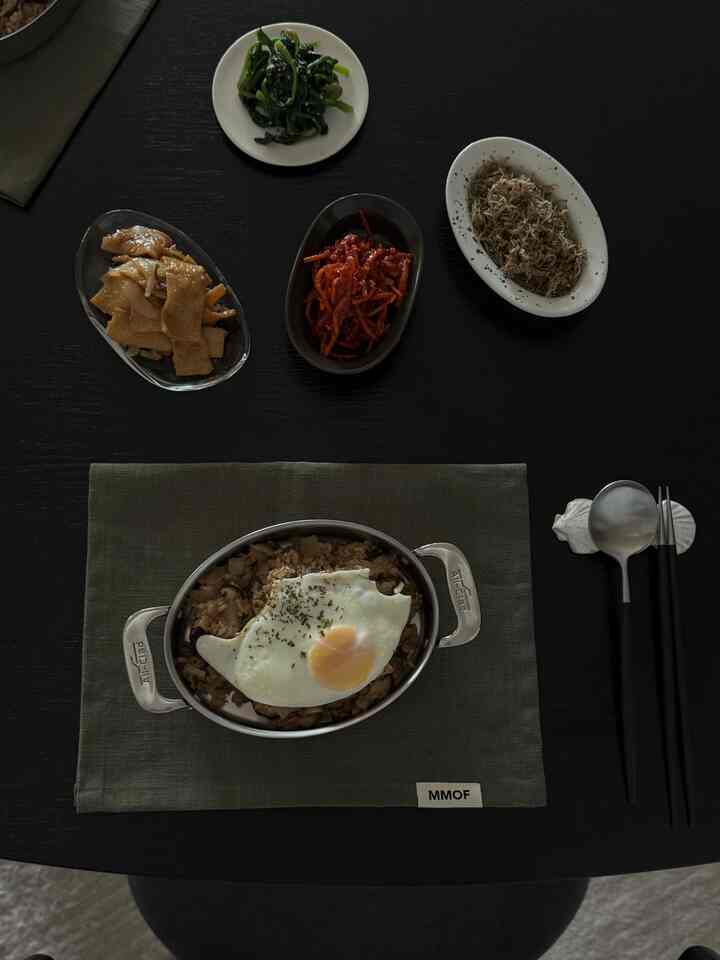 黒いダイニングテーブルに韓国料理の副菜と目玉焼きが並べられた雰囲気のあるインテリア