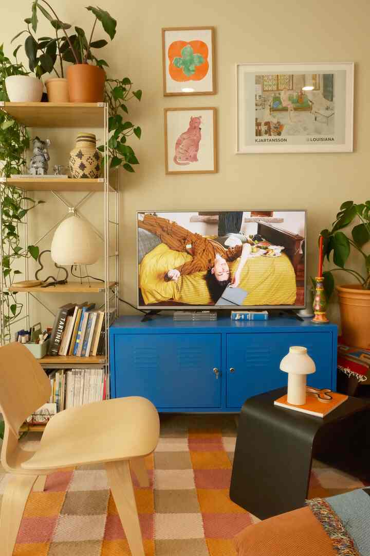 ベージュの壁とブルーのキャビネットが調和したリビング、植物とウォールアートが配置された雰囲気のある空間