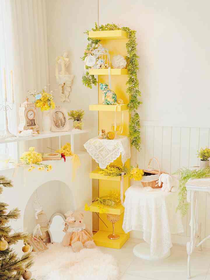 黄色い棚と白い家具、黄色の花と緑の植物が調和したヴィンテージ風のリビングルームインテリア