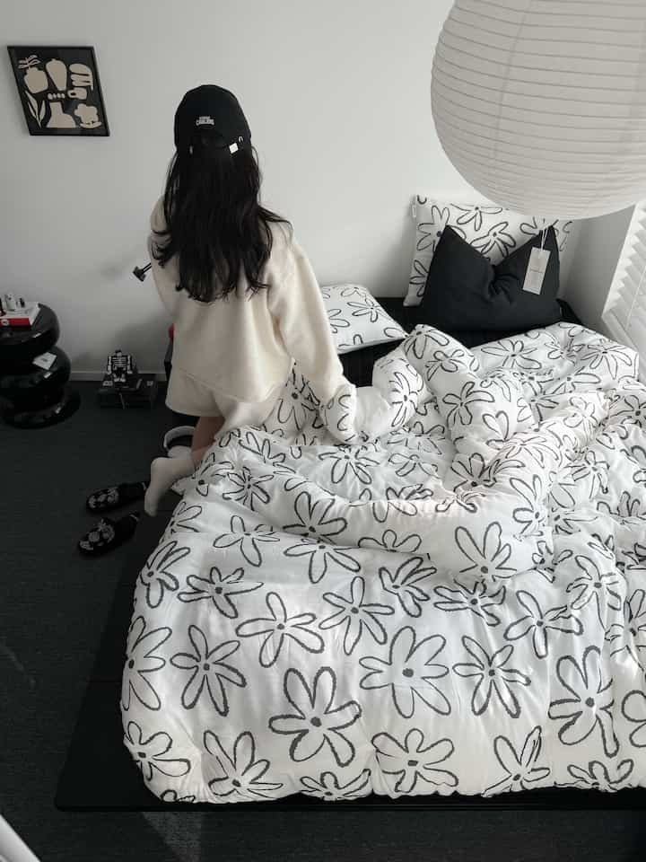 白と黒のトーンの寝室、花柄の寝具とミニマルな家具が配置されたモダンな空間