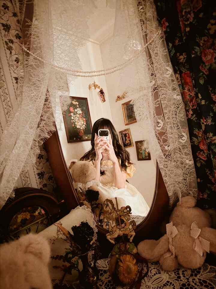 ナチュラルカラーの小さな部屋、大きな木製鏡とレースカーテンが配置された雰囲気のあるヴィンテージ空間