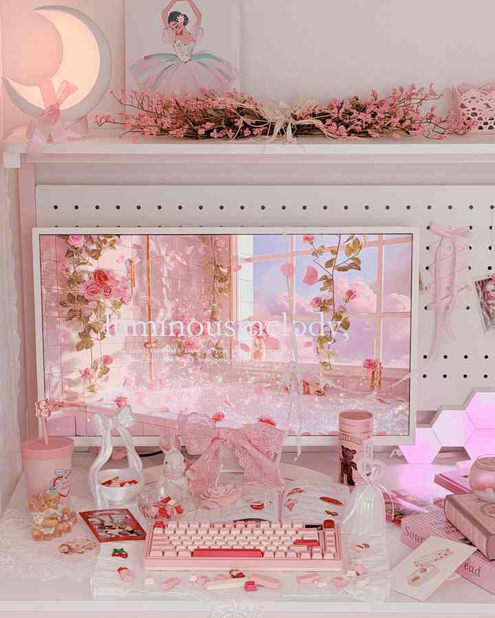 パステルピンクとホワイトのトーンでまとめられたホームオフィス。ピンクのキーボード、ピンクの花のガーランド、バレリーナのポスターが配置された印象的なデスク。」