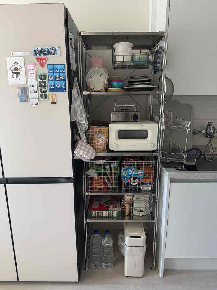 白い壁とキッチンに配置されたステンレス製の棚、食器やトースター、食料品が整頓された雰囲気のあるインテリア