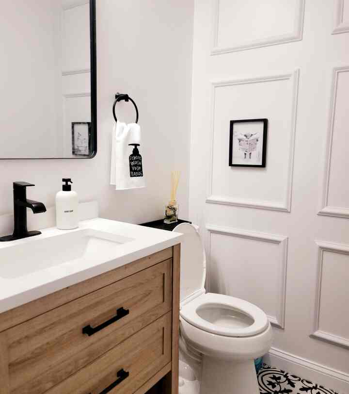 White and brown toned bathroom featuring a wooden vanity with white sink, sleek black faucet, and towel ring, creating a clean modern atmosphere