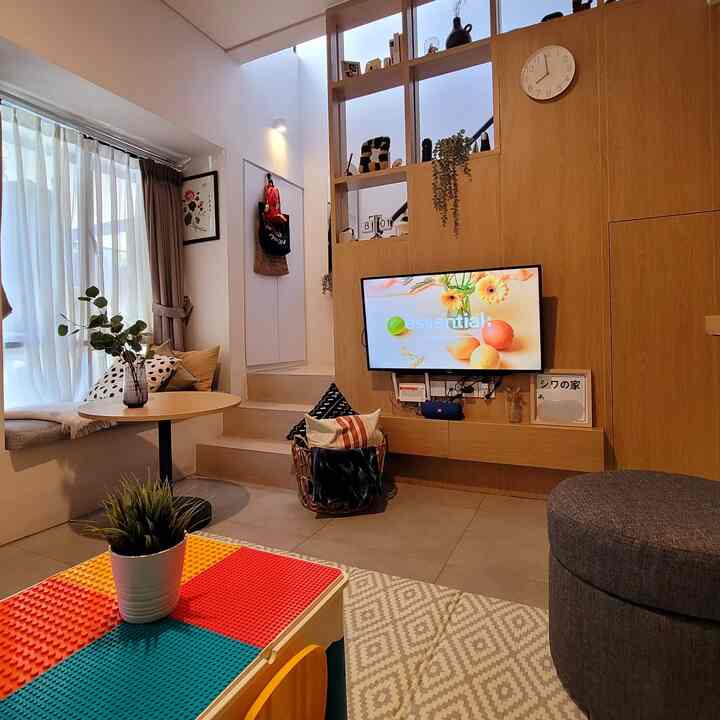 Natural tone living room featuring wooden walls, foldable playmat, and TV, creating a cozy space