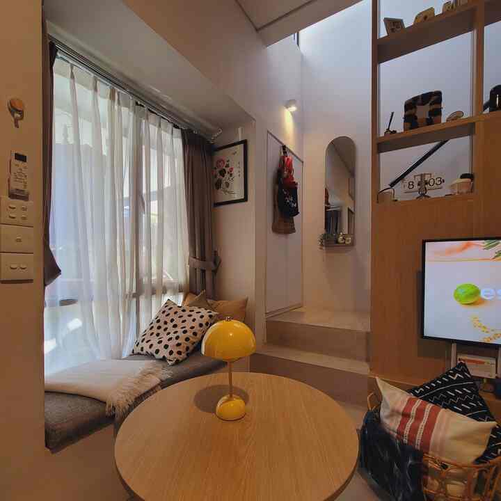 Natural wood-toned compact living room featuring a yellow table lamp and cushions with cozy atmosphere