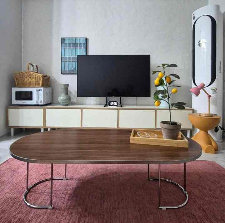 白を基調としたナチュラルな色調のリビング、モダンなコーヒーテーブルとテレビ台、植物やフロアランプが配置された雰囲気のあるインテリア