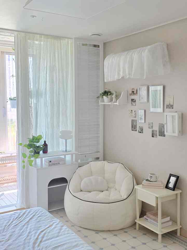 ホワイトとブラックのアクセントがある寝室、ブークレ素材のビーズクッションソファとシンプルな家具が配置された居心地の良い空間