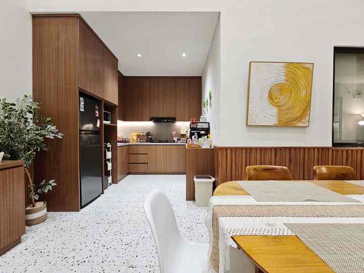 Modern kitchen and dining room with white walls and wood-tone cabinetry, terrazzo flooring, and table runners creating a cozy atmosphere