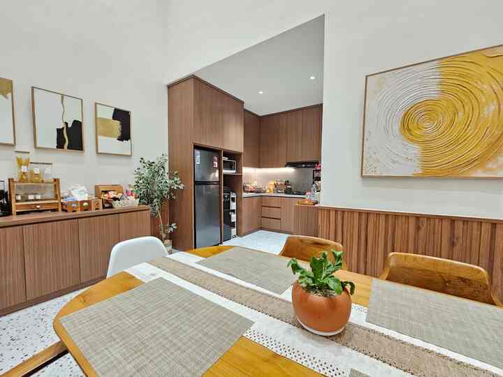 Natural brown-toned kitchen and dining room featuring wooden dining table and chairs, warm lighting, and abstract art creating a cozy atmosphere