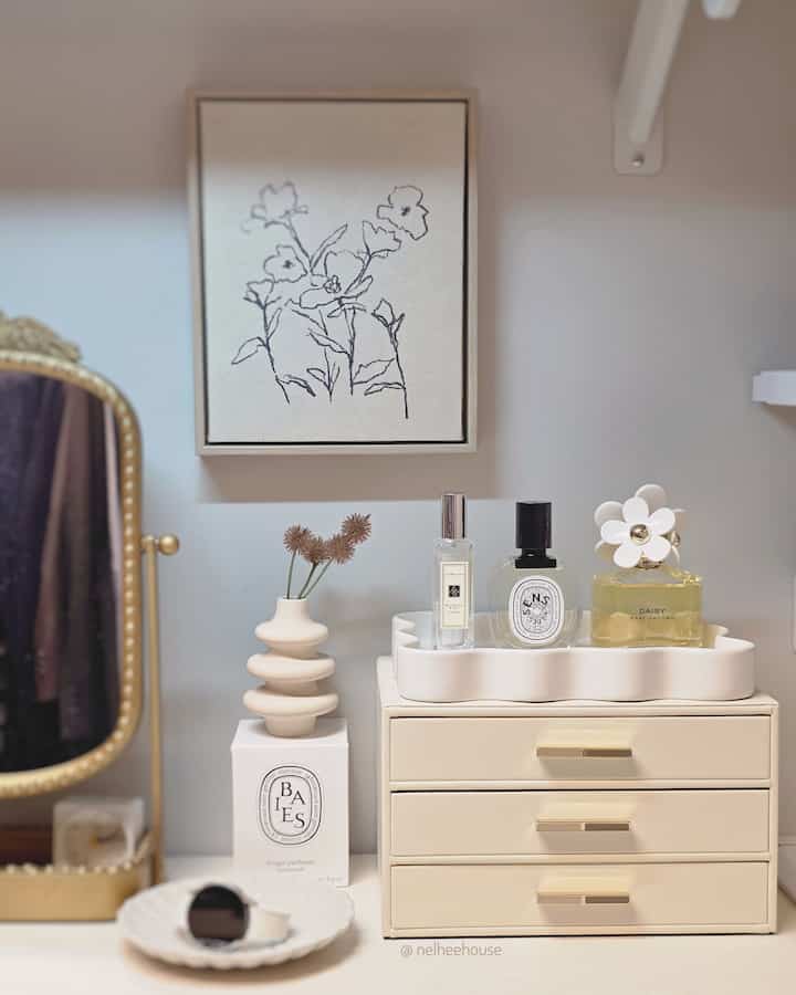 Beige and white-toned vanity space in front of a closet, featuring a scallop tray with perfume bottles neatly arranged at center