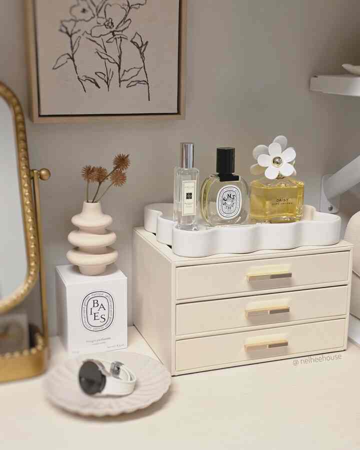 Ivory-toned vanity featuring candles, perfumes, vase, and tray in a minimal and tidy arrangement