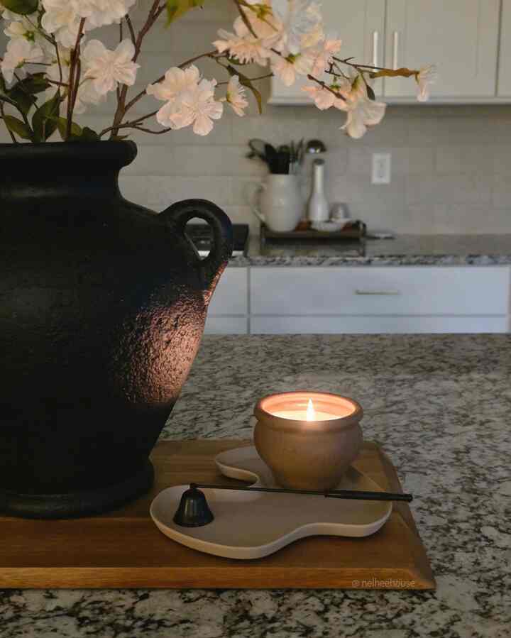 White tone kitchen featuring a wooden tray with a lit candle, showcasing a natural modern interior style