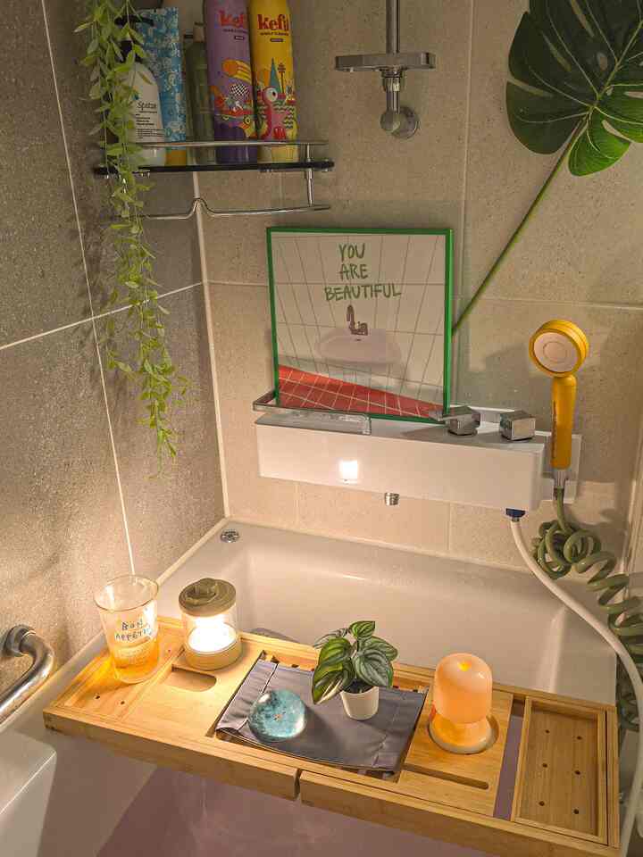 ベージュとホワイトのトーンが映えるバスルーム、浴槽上のウッドトレイにキャンドルと植物が置かれた雰囲気のあるインテリア