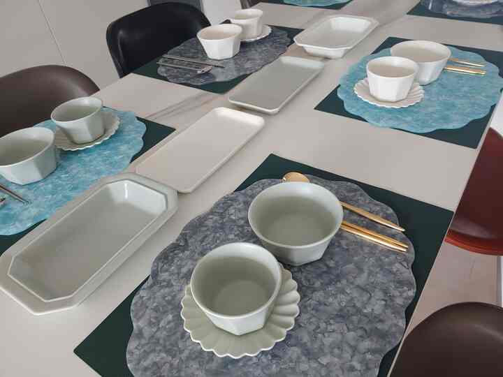 Modern dining space featuring white and gray matte bowls with decorative placemats on a clean dining table