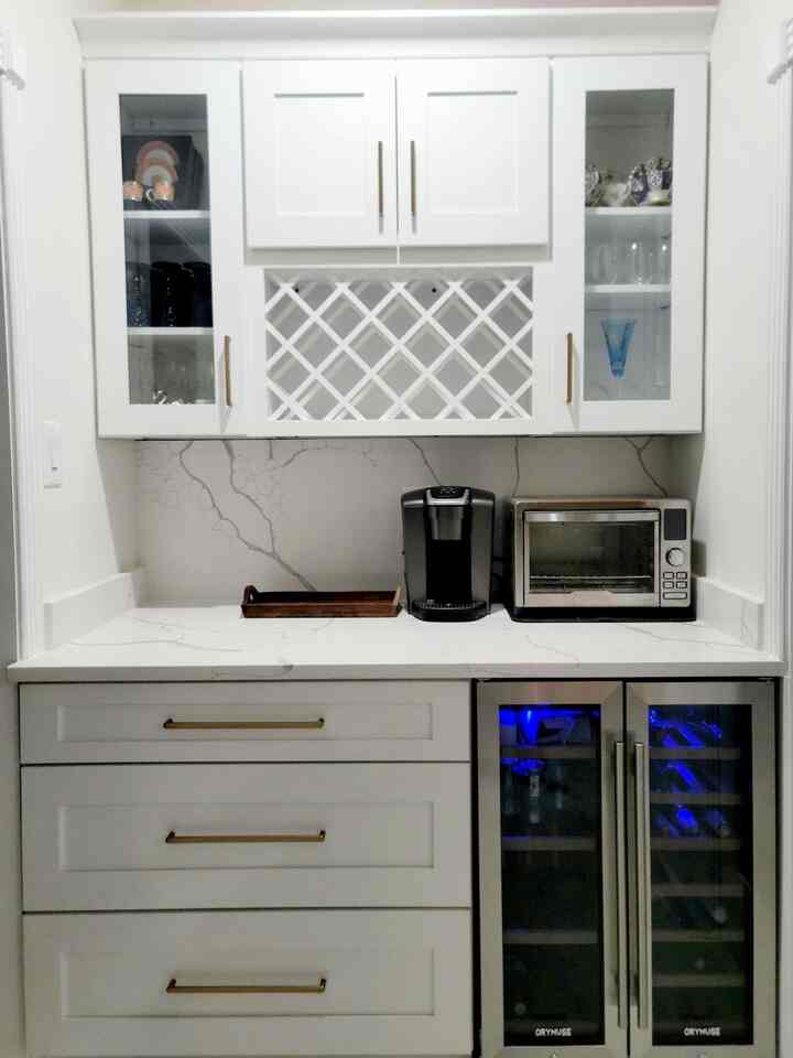 We’re really enjoying this little wet bar corner—white cabinets, a small wine and drink fridge, a wine rack, and glass-door storage. It’s simple, but it works perfectly for us #wetbar #wine #minifridge #winerack #whiteinterior #kitcheninterior #kitchentile 