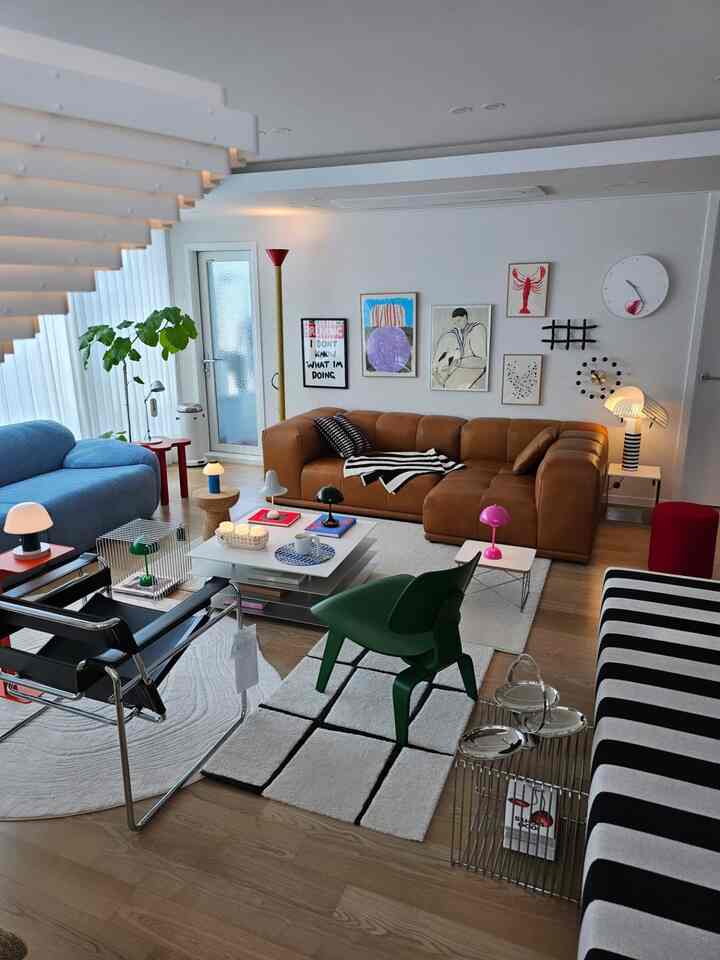 ウッドトーンの床とブラウンレザーのソファ、ブルーの曲線ソファが配置されたモダンなリビングルーム