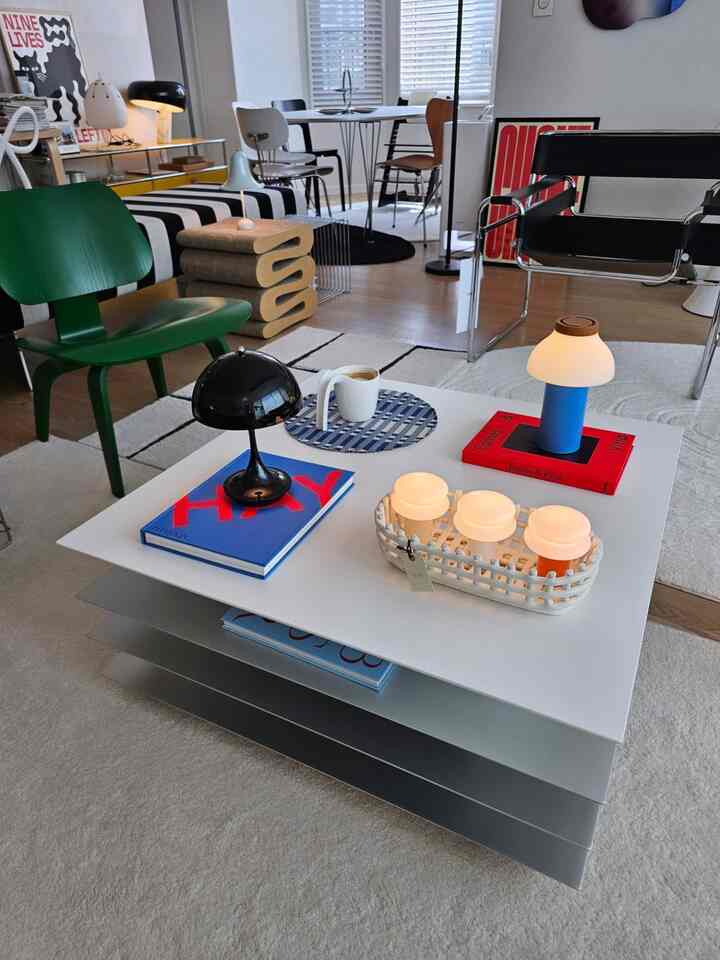 Modern living room with white and black harmony, featuring blue and green accent chairs and various table lamps for a stylish atmosphere