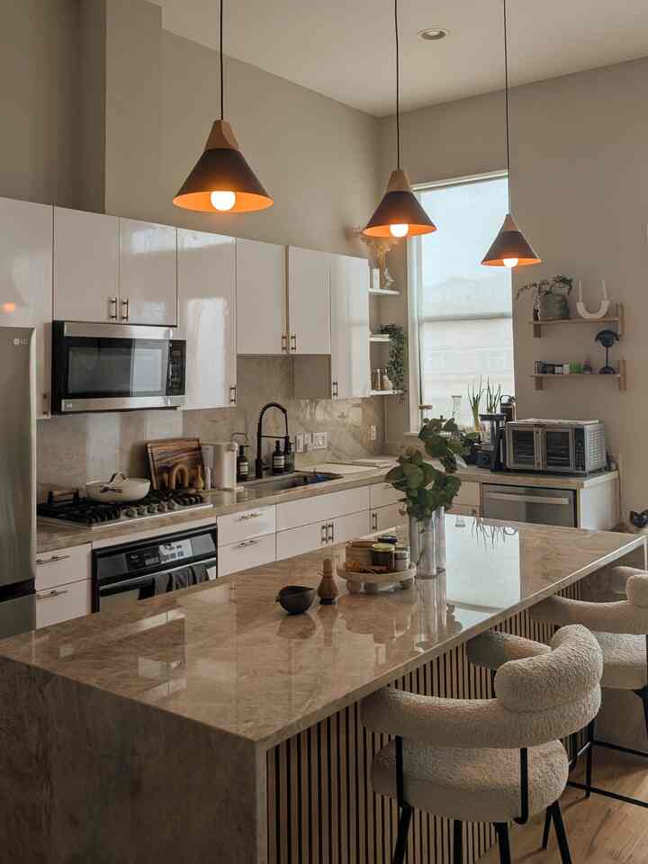 Natural-toned kitchen space featuring a marble waterfall kitchen island and cozy bar stools in a warm, inviting interior