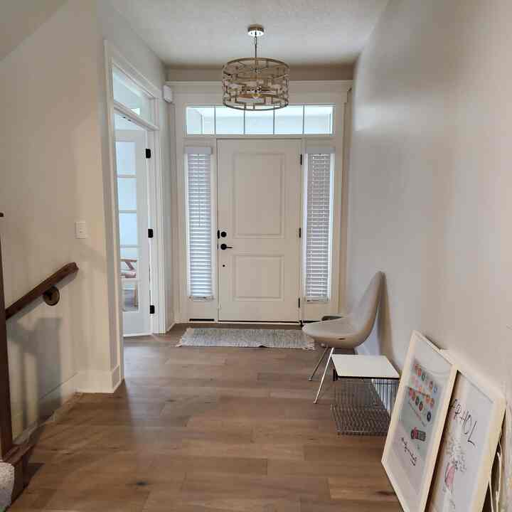 White and wood tone entrance featuring a simple chair and side table in a minimalist space