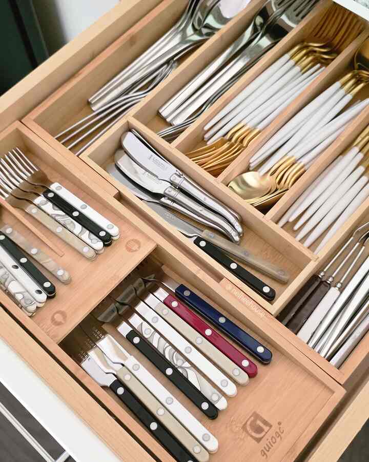 Wood tone kitchen drawer neatly organized with various designs of cutlery sets
