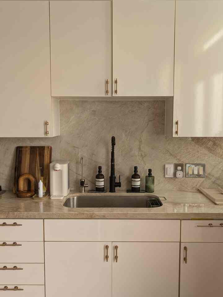 these adjustable cabinet pulls perfectly complement the natural stone textures and soft, neutral tones, creating a warm and inviting kitchen atmosphere! #neutral #champagnegold #wood #stone #kitchen