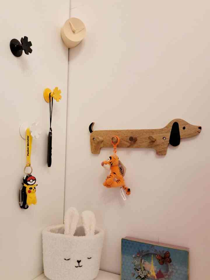 White walls with corner-mounted dog-shaped wall rack and clock, yellow and black hooks create a cozy storage nook