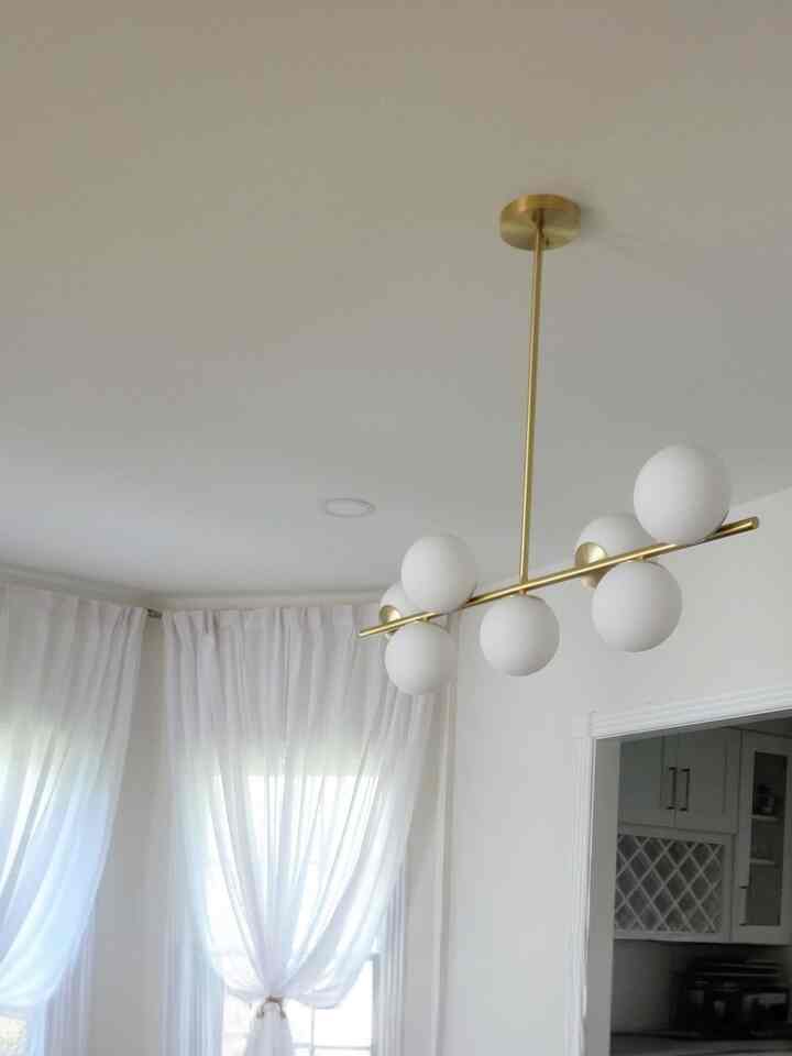 Bright modern interior in white and gold tones featuring a central pendant light fixture