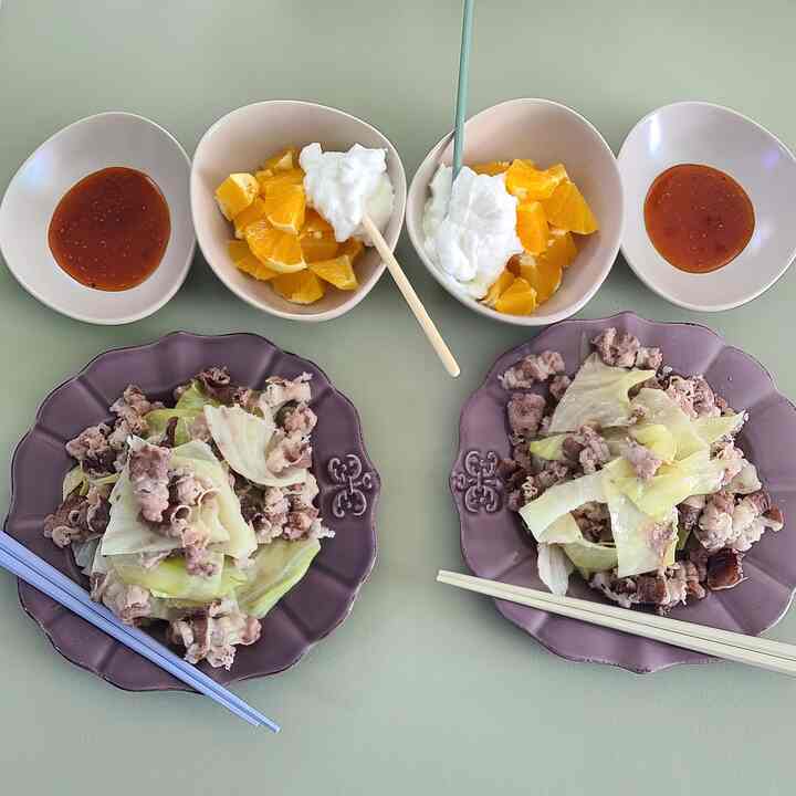 淡いグリーンのテーブルにヘルシーなホームブランチが並び、二つの皿と果物のボウルがミニマルに配置された雰囲気のあるインテリア