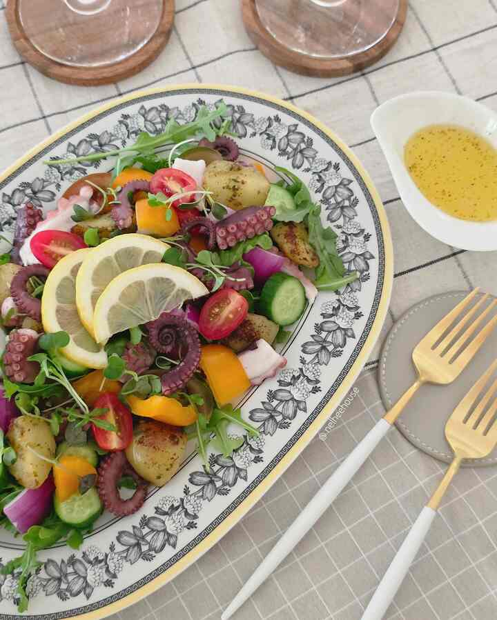 White and gold accented dining setup featuring plated octopus salad with fresh vegetables, evoking a healthy eating atmosphere