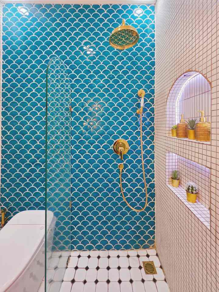 Modern bathroom space with blue scallop-patterned tile wall and gold shower fixtures