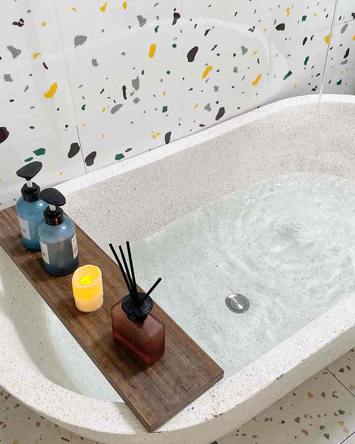 White-toned bathroom featuring a bathtub with a wooden tray holding candle and diffuser, creating a cozy atmosphere