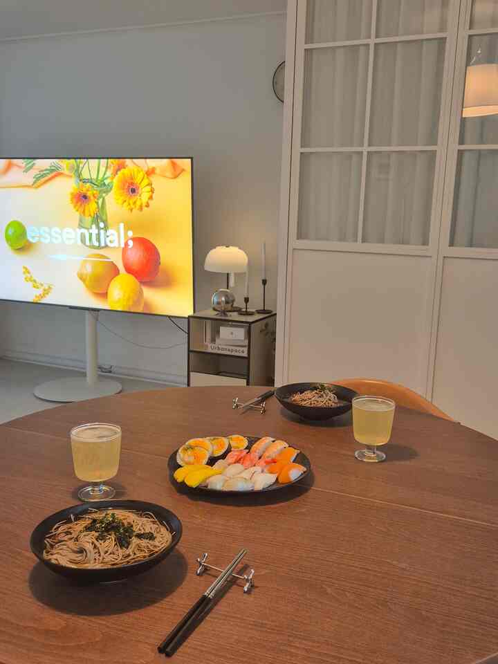 ナチュラルなブラウンのウォールナットダイニングテーブルと黒い器が配置されたリビング、清潔でモダンな雰囲気のあるインテリア