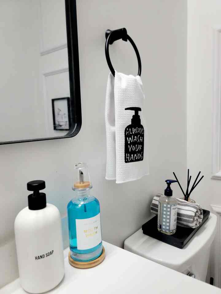 White and wood tone bathroom with neatly arranged hand soap, towel, mouthwash, and diffuser creating a modern atmosphere