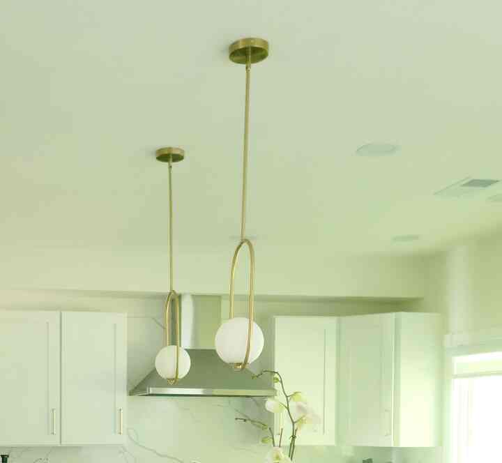 Gold-toned kitchen space featuring gold pendant lights centered with modern, bright atmosphere